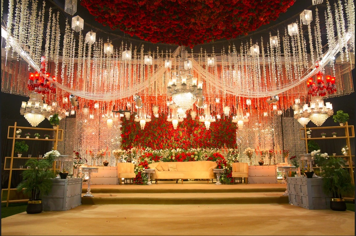 Barat decor in Lahore by VenueHub with red floral ceiling chandeliers and bridal stage